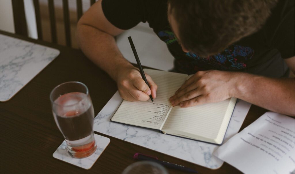 man makes a task list on a journal