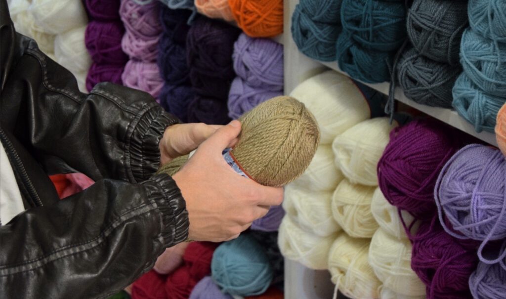person touching yarn at a yarn store